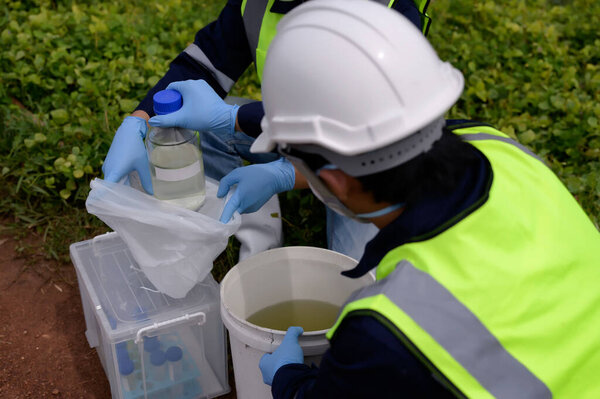 Инженеры-экологи берут образцы воды, которые плохо пахнут на ферме у природных источников воды положить их в бутылку и держать в пластиковых пакетах, вода загрязнена токсичных подозрительных загрязнений.