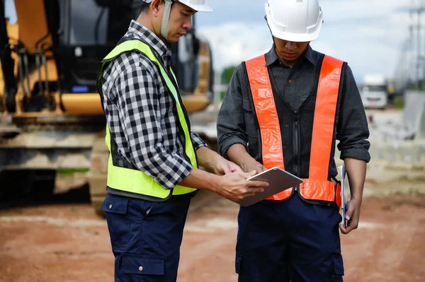 Highway Engineer Consultant and Young engineer planning work together with a technology tablet at the road construction site. Management inspects construction projects in workflow and business.
