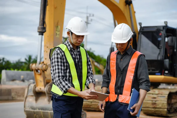 Highway Engineer Consultant and Young engineer planning work together with a technology tablet at the road construction site. Management inspects construction projects in workflow and business.