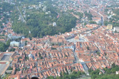 Tarihi kent meydanında saat kulesi ve ortaçağ mimarisi ile Romanya 'nın Brasov kentinin tarihi kısmının Tampa Dağı manzarası.