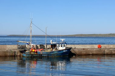 Kuzey kıyısında mavi gökyüzü olan İskoçya 'daki John O' Groats 'ta renkli eski bir balıkçı teknesi.
