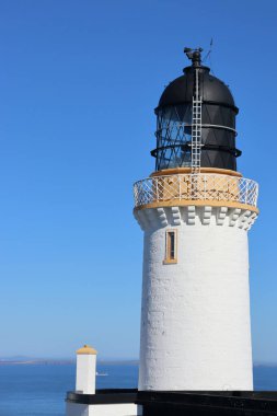 Kuzey kıyısı İskoçya 'da beyaz sarı ve siyah deniz feneri. Dunnet Head' de mavi gökyüzü arka planında.