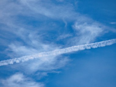 Geniş mavi gökyüzü yumuşak, ince beyaz bulutlarla dolu, dingin ve açık bir atmosfer yaratıyor..