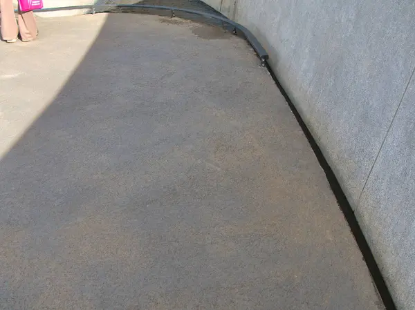 Üzerinde gölge olan düz beton bir yol, basit tasarıma doku ve görsel derinlik ekliyor.