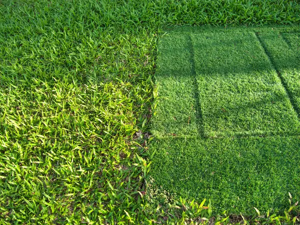 Oyun parkında metal parmaklıkları olan yeşil yapay bir çim tepesi, renkli yüzey ve kentsel binalarla çevrili..