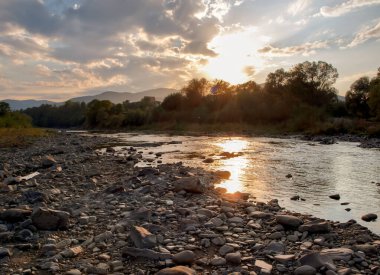 Karpatlar 'da bir dağ nehrinin üzerinde gün batımı ve sudaki yansıma