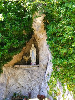 Yeşilliklerle çevrili taştan bir mağarada Madonna