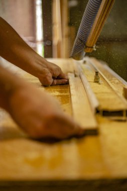 Yuvarlak testerenin yanındaki tahtayı tutan elleri kapatın.