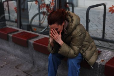 Kız başını tutup yüzünü kapatıyor. Baş ağrısı. Sorunlar ve keder. Yardım gerekiyor. Kız yalnız oturuyor..