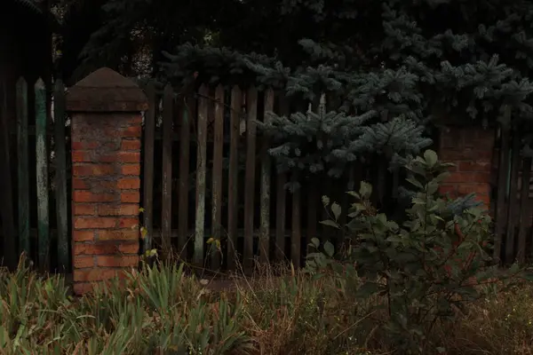 Tuğla sütunları olan ahşap bir çit zarif ve şık görünür. Tahtanın doğal güzelliğiyle tuğla dayanıklılığını birleştirir..