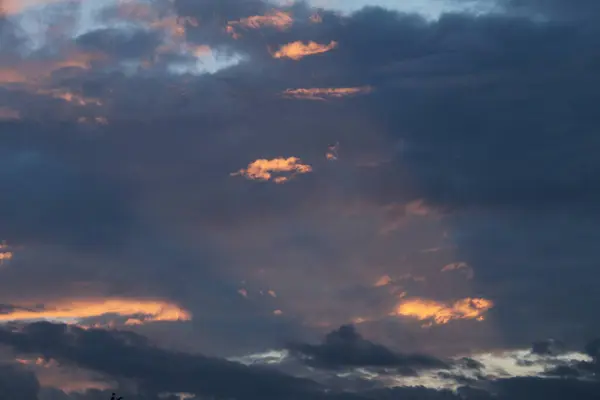 Güneş ışığı karanlık bulutları delip geçer ve ışık ile gölge arasında çarpıcı bir kontrast yaratır. Altın ışınlar küçük bir bölgeyi aydınlatıyor, kasvetli bir güne sıcaklık ve umut getiriyor..