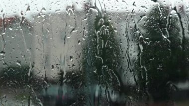Şiddetli bir gökyüzünü yansıtan yağmur damlaları pencere camından aşağı süzülüyor. Yavaşça düşen yağmur damlalarının yakın çekimi rahatlatıcı ve meditasyon yapan bir atmosfer yaratır..