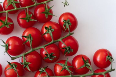 Bitki temelli diyet için beyaz bir zemin üzerinde olgun kiraz domatesleri. Doğal kaynaklı taze sebzeler. Vejetaryenler ve organik ürün meraklıları için mükemmel bir seçim..