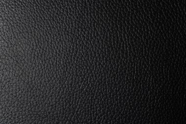 Pürüzsüz, siyah, sahte deri bir yüzeye yakın plan. Pürüzsüz siyah sahte deri monokrom dokusu ve çok az dokusu var. Bu malzeme modern ve şık ürünler için mükemmeldir..