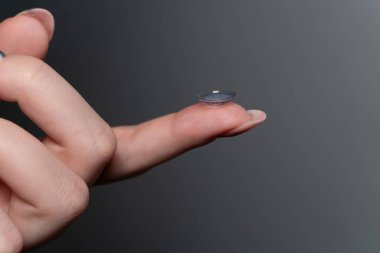 Parmak ucunda kontak lens tutan bir kadının yakın plan fotoğrafı. Kontakt lensler kolaylık ve çok yönlülük sunar. Kontak lensler miyopluğu ve hipermetrobu da düzeltebilir.. 