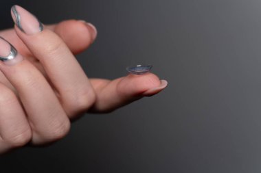 Parmağına lens takan bir kadının yakın plan fotoğrafı var. Göz bakımı. Göz sağlığı hizmetleri, göz sağlığının korunmasında önemli bir rol oynamaktadır..