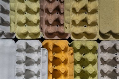 A close-up of green, white, yellow, and brown egg cartons highlights the eco-friendly texture of recycled materials. This image demonstrates how simple recycling efforts can contribute to a more sustainable lifestyle. clipart