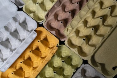 Geri dönüşümlü kağıttan yapılmış renkli yumurta karton yığını, çevre dostu malzemelerin dokusunu vurguluyor. Bu ambalaj geri dönüşümü teşvik eder ve sürdürülebilir bir yaşam tarzının önemini vurgular.