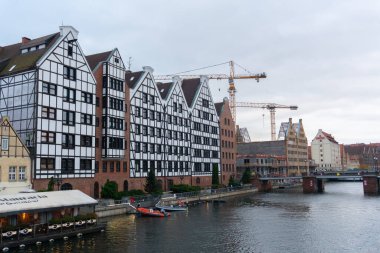 Gdansk 'ın merkezindeki Motlawa Nehri rıhtımının panoramik bir görüntüsü, Prusya duvar stilinde binaların ayırt edici cephelerini içeriyor. Gdansk, Polonya - 3 Kasım 2024