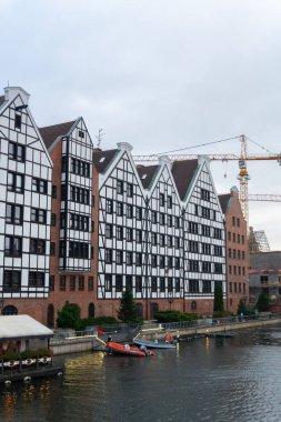Gdansk 'ın mimari ahengi: geleneksel tarz evler Motlawa' nın sularına kentsel gelişim belirtileriyle birlikte yansıtılır. Gdansk, Polonya - 3 Kasım 2024