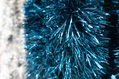 Işığın altında parıldayan metalik iplikçiklerin yoğun dokusuna sahip parlak mavi süslemelerin yakın çekimi. Serin mavi gölgeler kış tatilleriyle çok güzel eşleşir. Taze ve ışıl ışıl bir hava yaratır..