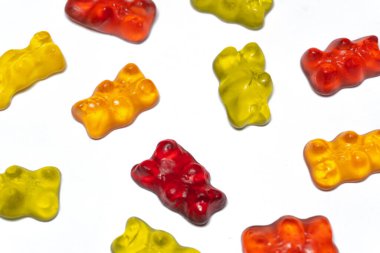 Renkli jelibonlar beyaz bir zemine saçılmış, her biri tatlı bir tat ve çiğnenmiş dokudan patlıyor, her ısırıkta yüzüne bir gülümseme getirmeye hazır.. 