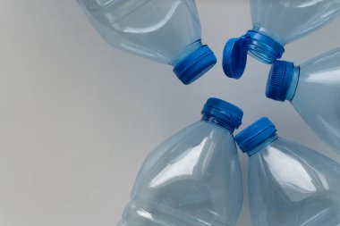 Mavi kapaklı altı plastik su şişesi daire şeklinde dizilmiş. Çevre koruma için atık ayrılmasının önemi. Düzenli ve düzenli düzenleme modern şişelerin rahatlığını ve uygun şekilde imha edilmelerinin önemini yansıtıyor..