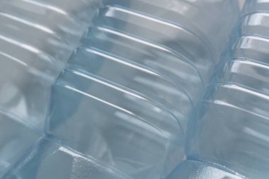 Odaklanan plastik şişeler: Yeniden kullanılmaya hazır, tırtıklı yüzeyi olan boş plastik şişelerin yakın çekimi, atıkların azaltılması için bilinçli bir yaklaşım sergilemektedir. Malzemenin şeffaflığı, yeniden kullanımdaki dayanıklılığını ve etkinliğini vurgular..