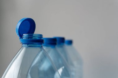 Mavi kapaklı bir grup plastik şişe beyaz arka planda sıraya dizildi. Mavi şapkalar bize tazeliği ve su içme ihtiyacını hatırlatıyor..