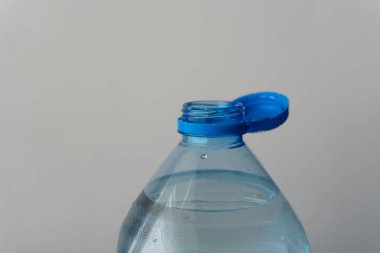 Boyun açıklığı olan su şişesi, düz bir duvara karşı plastik kabı minimalist bir estetiği yansıtarak ağzına kadar doldurur. Sıcak bir günde susuzluğunu gidermeye davet ediyor gibi görünüyor..