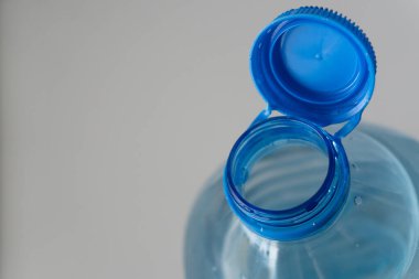 Plastik bir şişenin ayrıntıları: Yakın planda açık bir şişenin boynu, düşmek üzere olan bir damla su, canlandırıcı bir hava iletir..