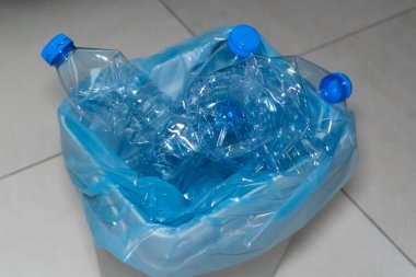 Çevresel mesele: Mavi kapaklı plastik şişelerle dolu beyaz plastik bir çöp kutusu. Fotoğraf, sorumlu imha ve atık ayıklama ihtiyacının bir hatırlatıcısı olarak kullanılıyor..