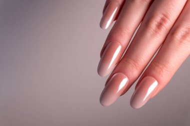 Hafif bir arka planda bir kadın elinin yakın plan maniküründe bir Babyboomer gradyanı. Tırnaklardaki zarif süt pembesi gradyanı karmaşıklığı ve minimalizmi vurguluyor..