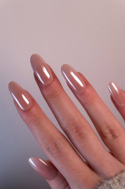 Bir kadının elinde süt pembesi bir gradyan olan şık ve zarif bir Babyboomer manikürü, yakın planda çekildi. Hafif arka plan manikür tasarımının güzelliğini vurguluyor..