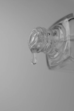 Şişeden bir yüzeye dökülen temiz tırnak cilası: Akan cila, onun eşit uygulamayı ve yüksek kaliteyi simgeliyor. Temiz cila şişeden güzelce dökülür, dokusunun pürüzsüzlüğünü ve parlaklığını vurgular..