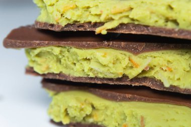 Dubai çikolatasının zarif bir dilimi bu tatlı çölün lezzetli yeşil şam fıstığı ve sütlü çikolatasının karışımını sergiliyor. Dubai çikolatasının her ayrıntısı ince tadı yansıtır. Makro çekim.