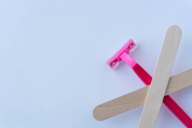 Tıraş yok: Ahşap spatula ile çizilmiş pembe bir jilet daha etkili ve güvenli alternatif bir saç kesme metoduna vurgu yapar..