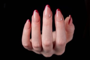 Tarz ve zarafet: Kusursuz bir burgundy manikürlü bir kadın eli derin siyah bir arka plana karşı. Işıl ışıl parlayan ışıl parlayan son lüks ve bakımlı güzelliği vurguluyor..