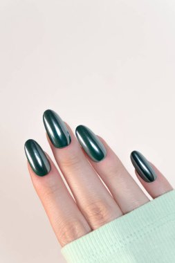 Oval tırnaklarda koyu yeşil manikürlü zarif bir avuç içi. Minimalizm ve sofistike bir çerçeve. İnce tadı vurgulayan..