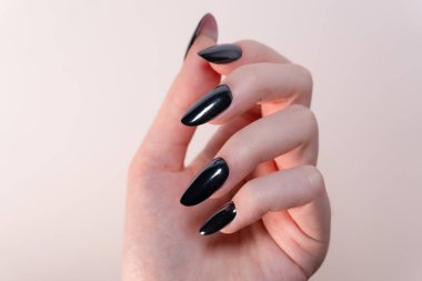 Beyaz arka plan sadeliğinde yakalanan oval tırnaklardaki siyah oje bir zarafetin sembolüne dönüştü. Cila ışığın altında parlıyor, manikürün zarif ve sofistike görünümünü arttırıyor..