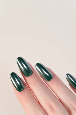 Beyaz arka planda zümrüt cilası olan bir elin yakın çekimi parlak bitiş ve yumuşak oval şekil kadınsı zarafet ve stili vurgular..