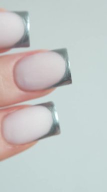 Keskin kare şeklinde, gümüş aksanlı bir Fransız manikürü. Temiz çizgiler ve parlaklıktan oluşan bir ahenk. Düzeni ve tarzı vurguluyor. Bu manikür kendine güveni ve ince bir tat alma duyusunu yansıtıyor..