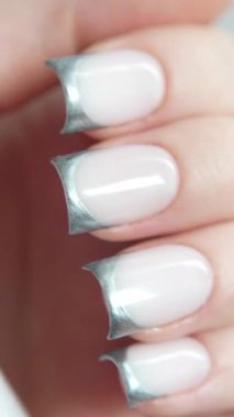 Süt bazlı makro bir video üzerinde parlak gümüş uçlu Fransız manikürü pürüzsüz parmak hareketleriyle estetiği ve profesyonelliği vurguluyor. Moda çekimleri ya da el işi reklamları için mükemmel bir seçim..