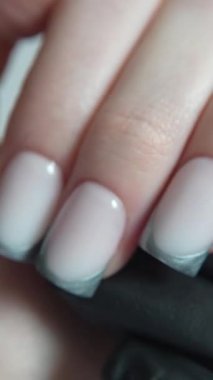 Sıcak süt bazlı serin metalik uçlu Fransız manikürü renk ve şekil uyumu. Manikürcünün siyah eldiveni görsel efekti arttırır ve elin şeklini özetler..