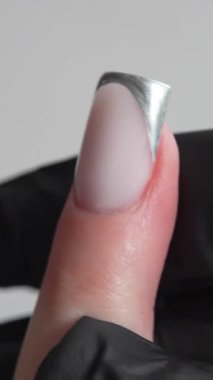 Metalik yansımalı Fransız manikürü ve her hareketinde yarı saydam taban minimalist zarafeti. Ressamın siyah eldiveni görsel yapı ekler ve çalışmanın hassasiyetini vurgular..