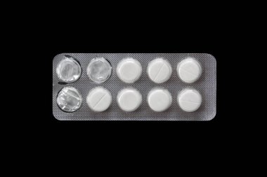Kabarcıklı beyaz tabletler. Ağrı kesiciler, antibiyotikler veya vitaminler için yakın plan tıbbi haplar koyu arka planda izole edilir..