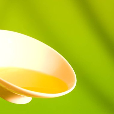 Bowl with olive oil on green background clipart