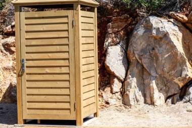 A changing cabinet positioned against a rugged rock background, blending practicality with the natural beauty of the stone surroundings. clipart