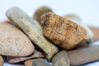 A close-up macro shot of smooth, colorful pebble stones arranged on a white background, showcasing their natural textures and intricate details. clipart