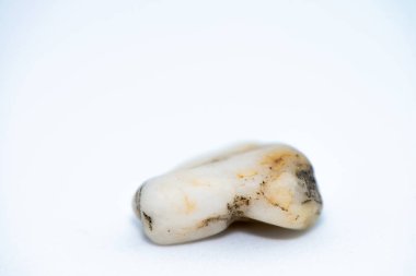 Beyaz zemin üzerine yerleştirilmiş pürüzsüz, renkli çakıl taşlarının yakın çekim makrosu doğal dokularını ve karmaşık ayrıntılarını gözler önüne seriyor..